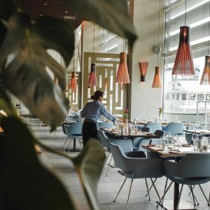 restaurangmiljö med servitris som dukar ett bord